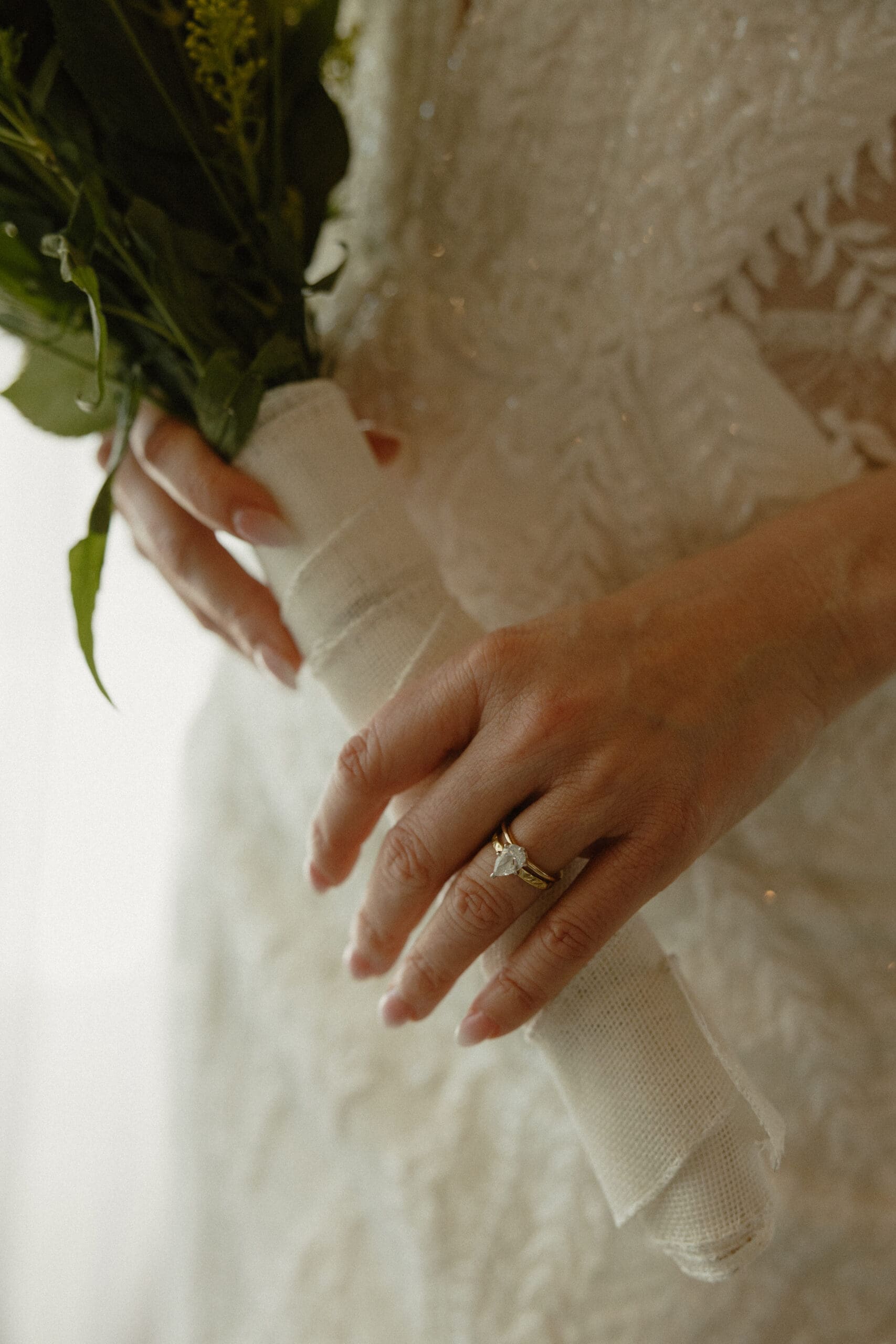 Close-up of bride's hand with wedding ring holding bouquet in lace gown, Fort Lauderdale wedding reception