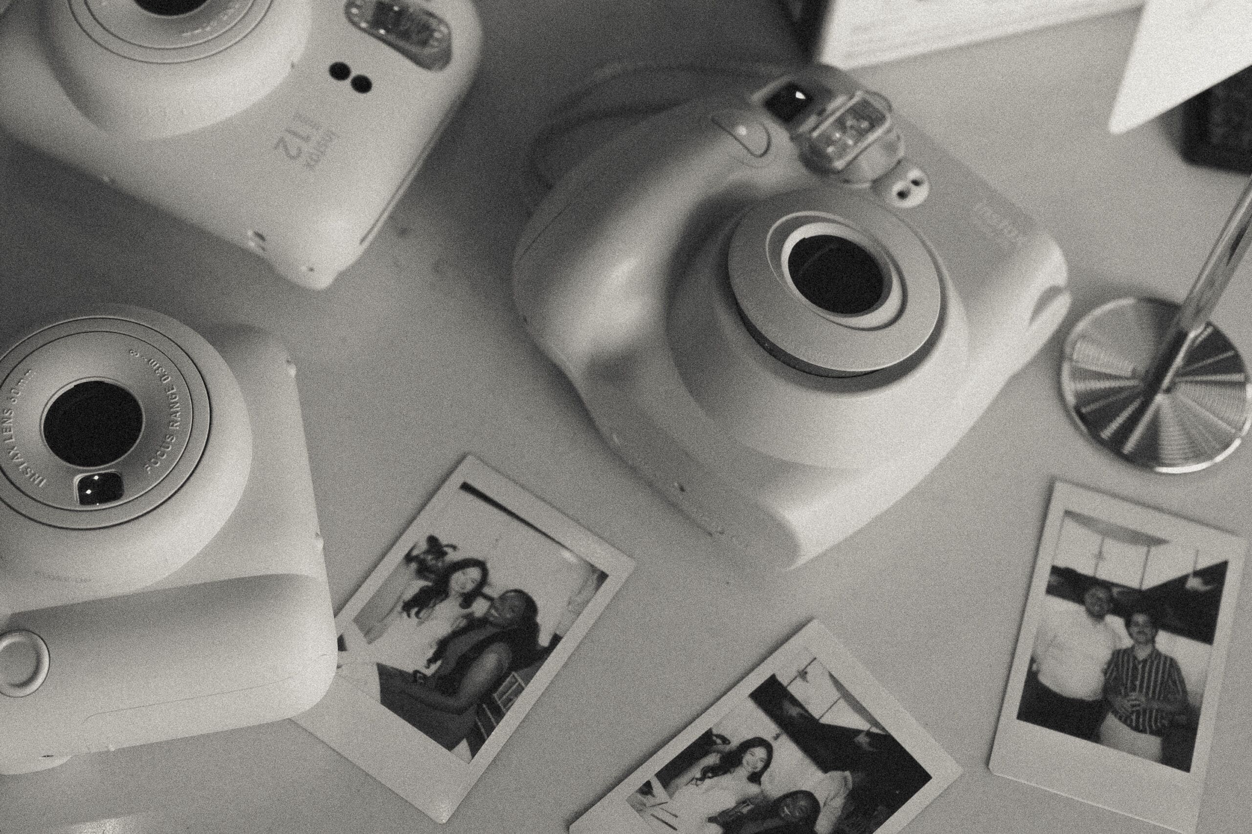 Black and white photo of instax cameras and polaroid prints at intimate wedding reception, Grateful Palate Fort Lauderdale