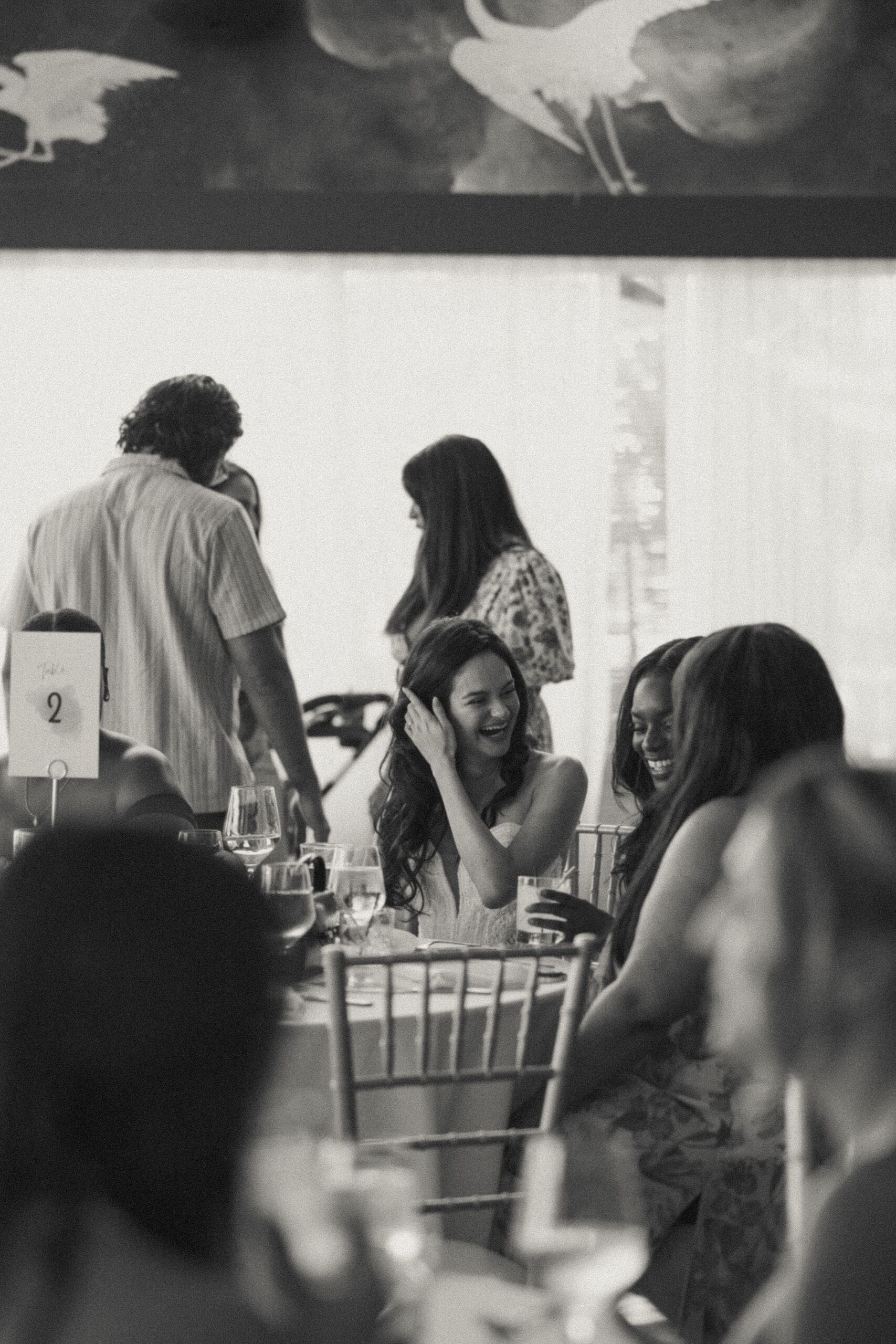 Black and white photo of wedding guests laughing at reception dinner table, Grateful Palate Fort Lauderdale